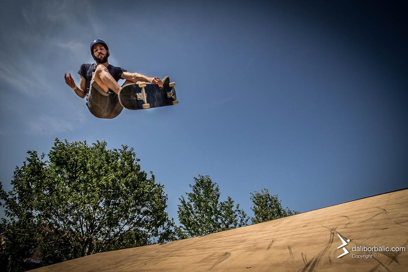 Uno skater in volo sopra la rampa, contro il cielo