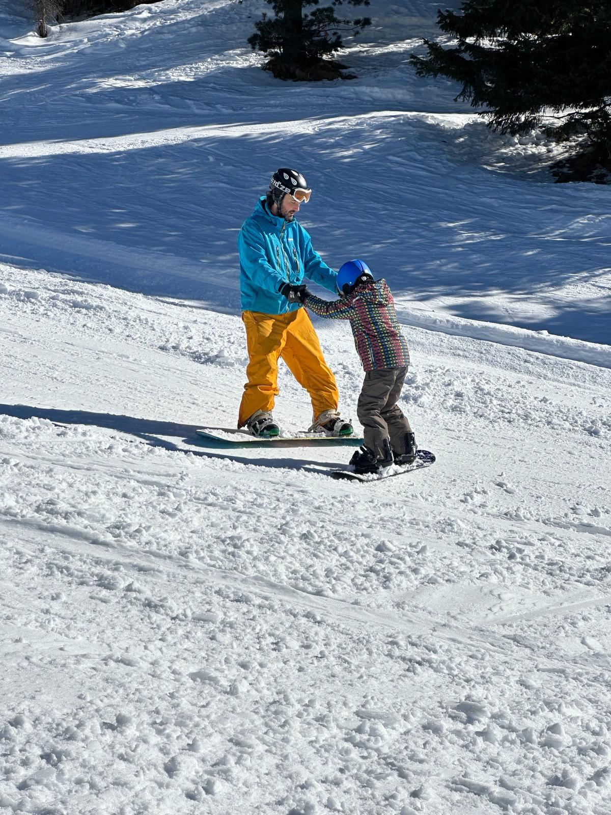 Un istruttore aiuta un bambino in piedi sullo snowboard