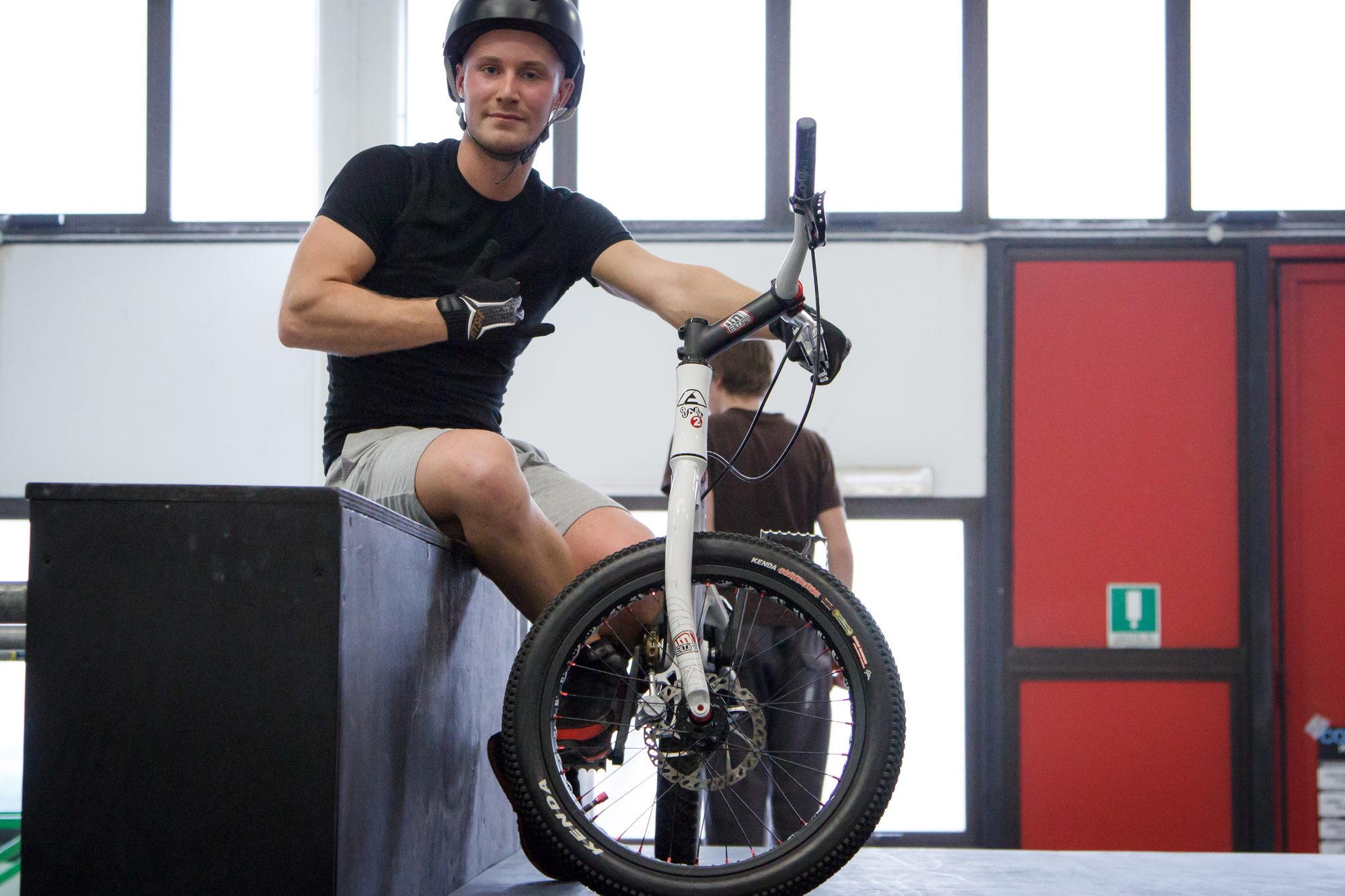 Ritratto di un rider seduto sulla sua bici da trial in palestra