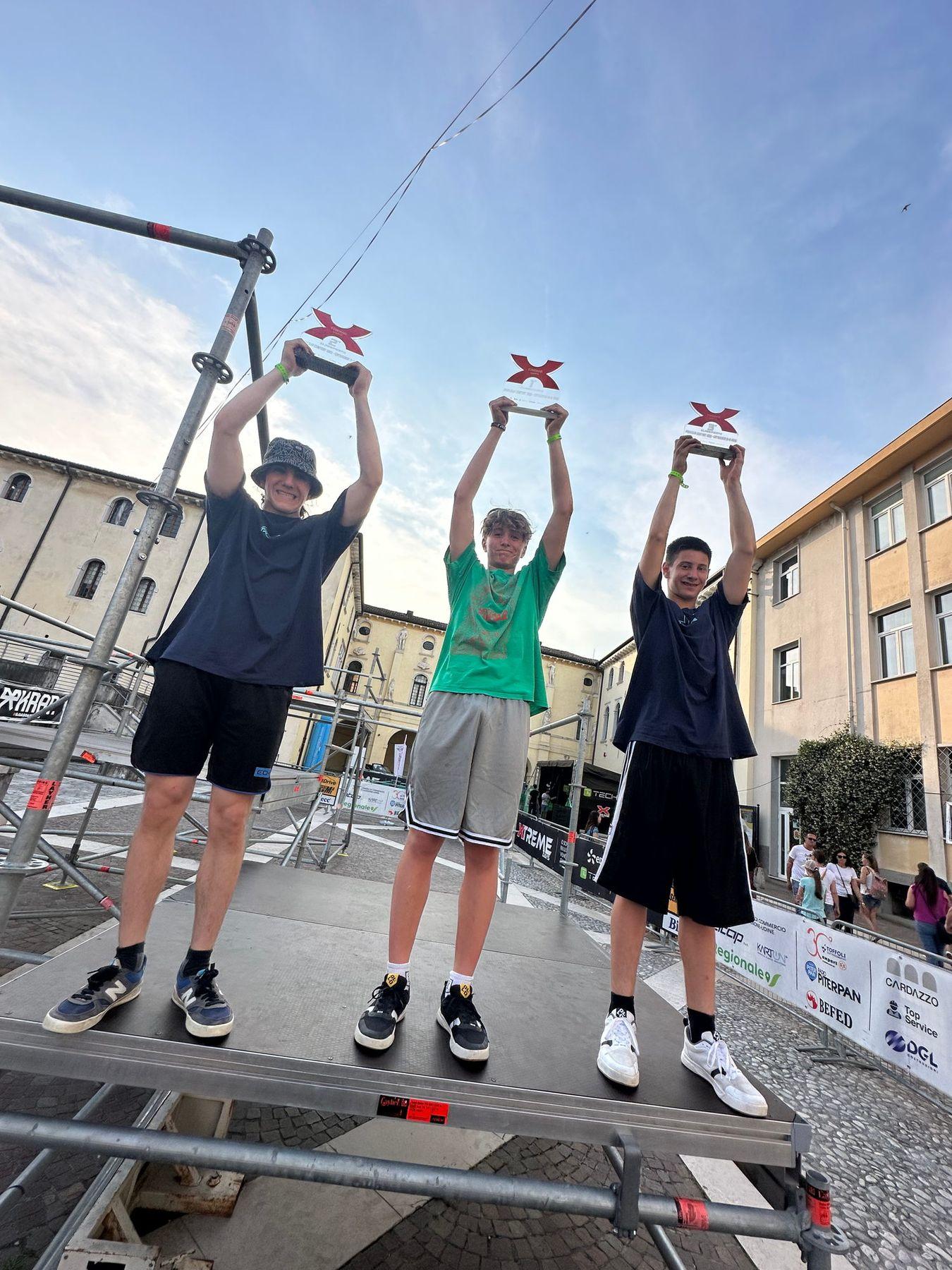 Tre atleti sul podio alzano i trofei verso il cielo