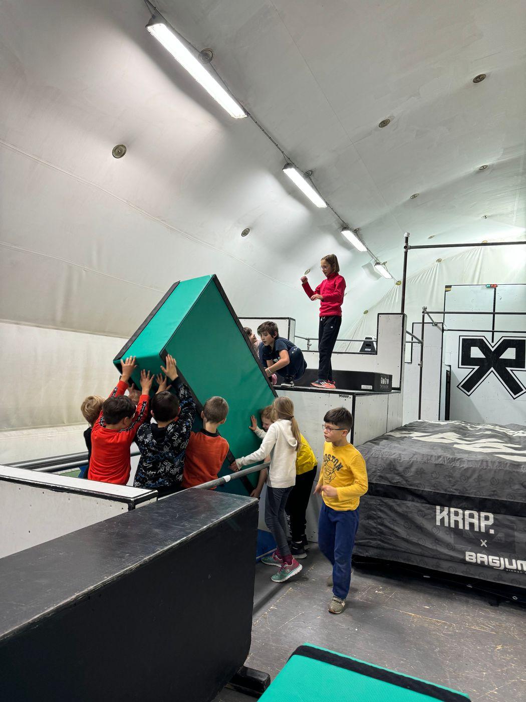 Una classe si arrampica insieme su una struttura della palestra, con l'istruttrice che segue dall'alto