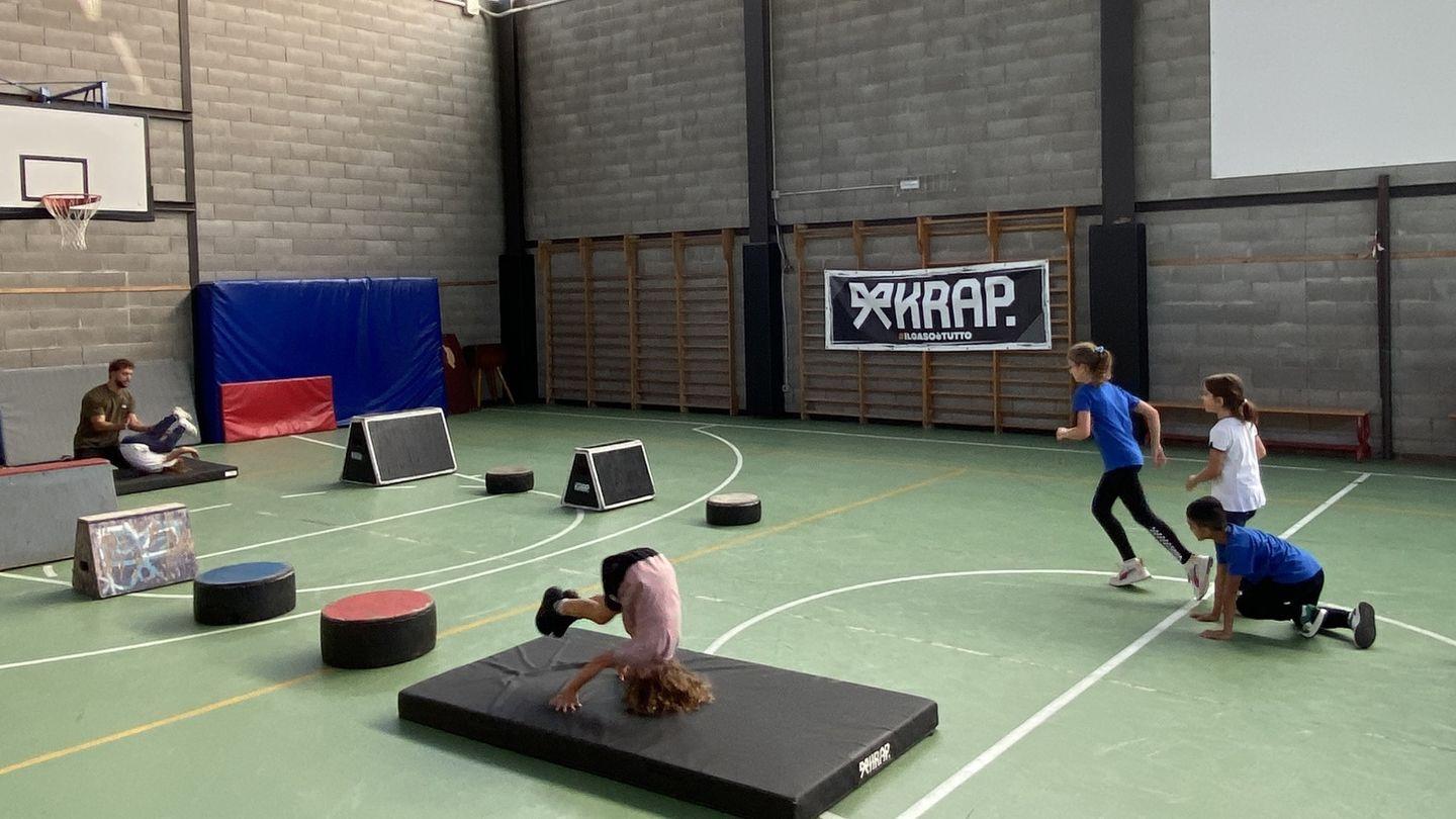 Una classe si allena sulle strutture KRAP montate nella palestra della scuola, sotto lo striscione dell'associazione