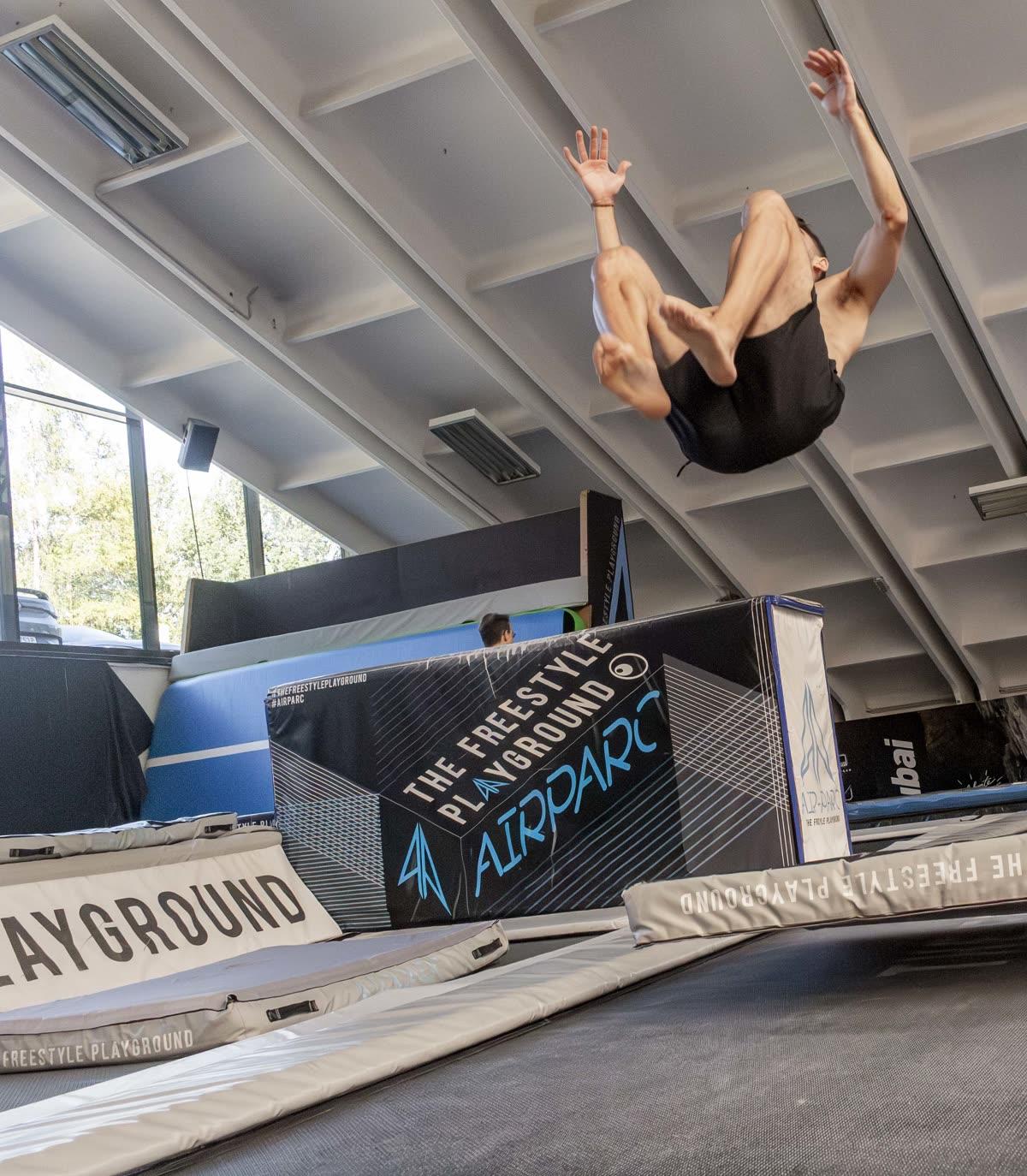 Un ragazzo del team in aria, raccolto, durante un salto all'indietro sul trampolino dell'Airparc