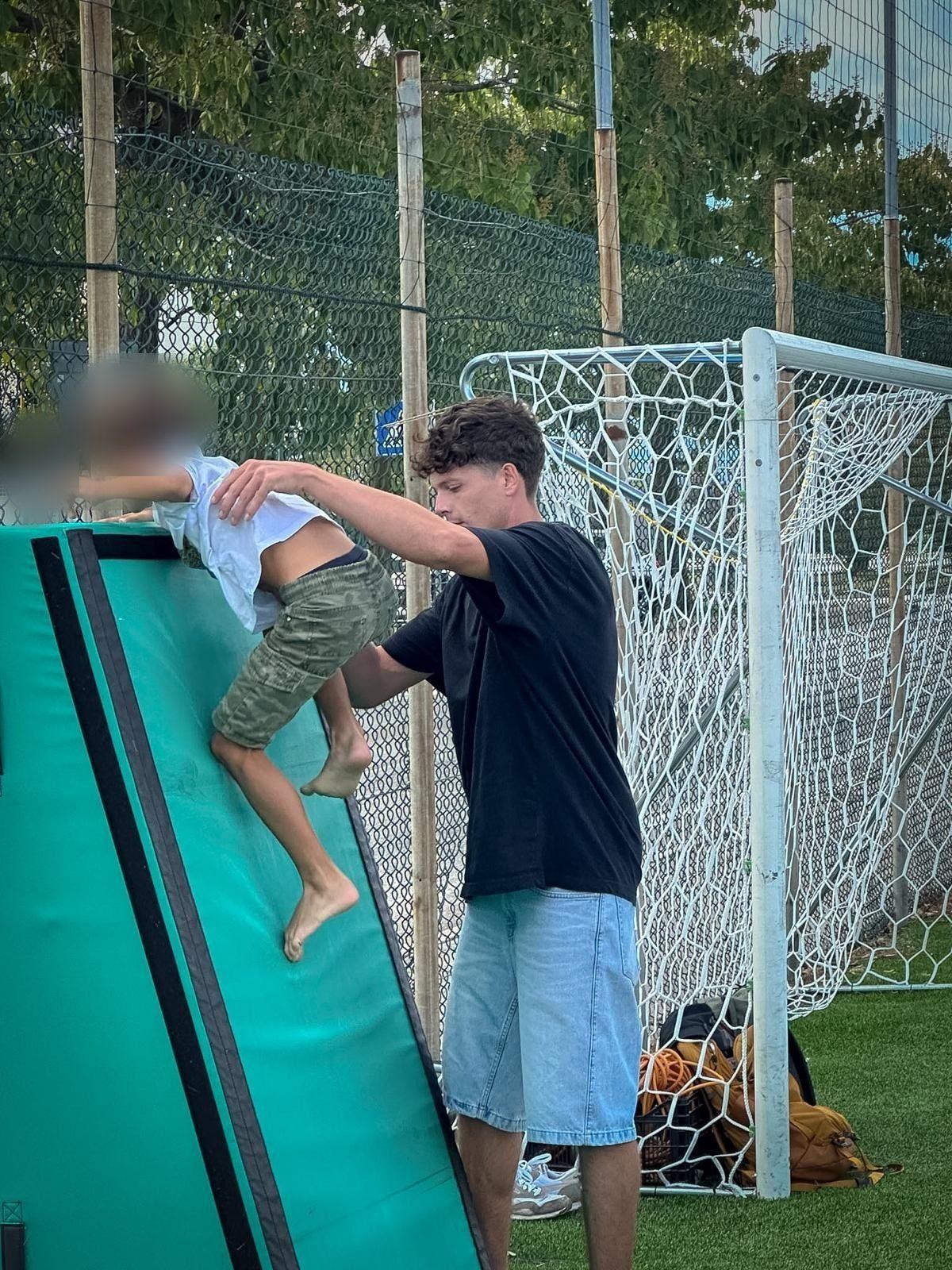 Un coach sostiene un bambino che sale su una rampa