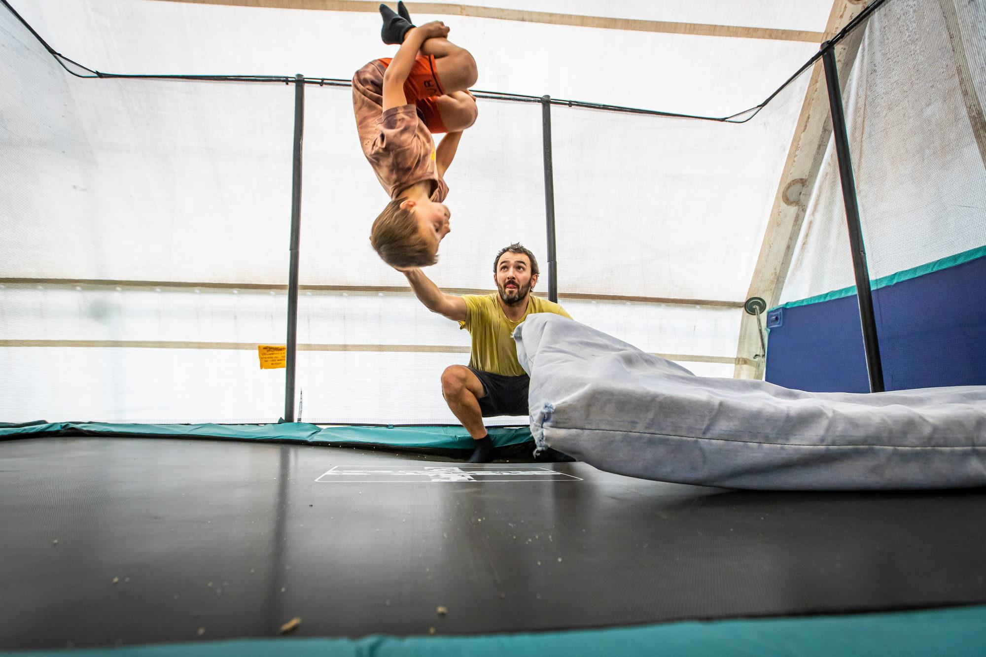 Un istruttore sostiene con le mani due bambini durante un salto acrobatico